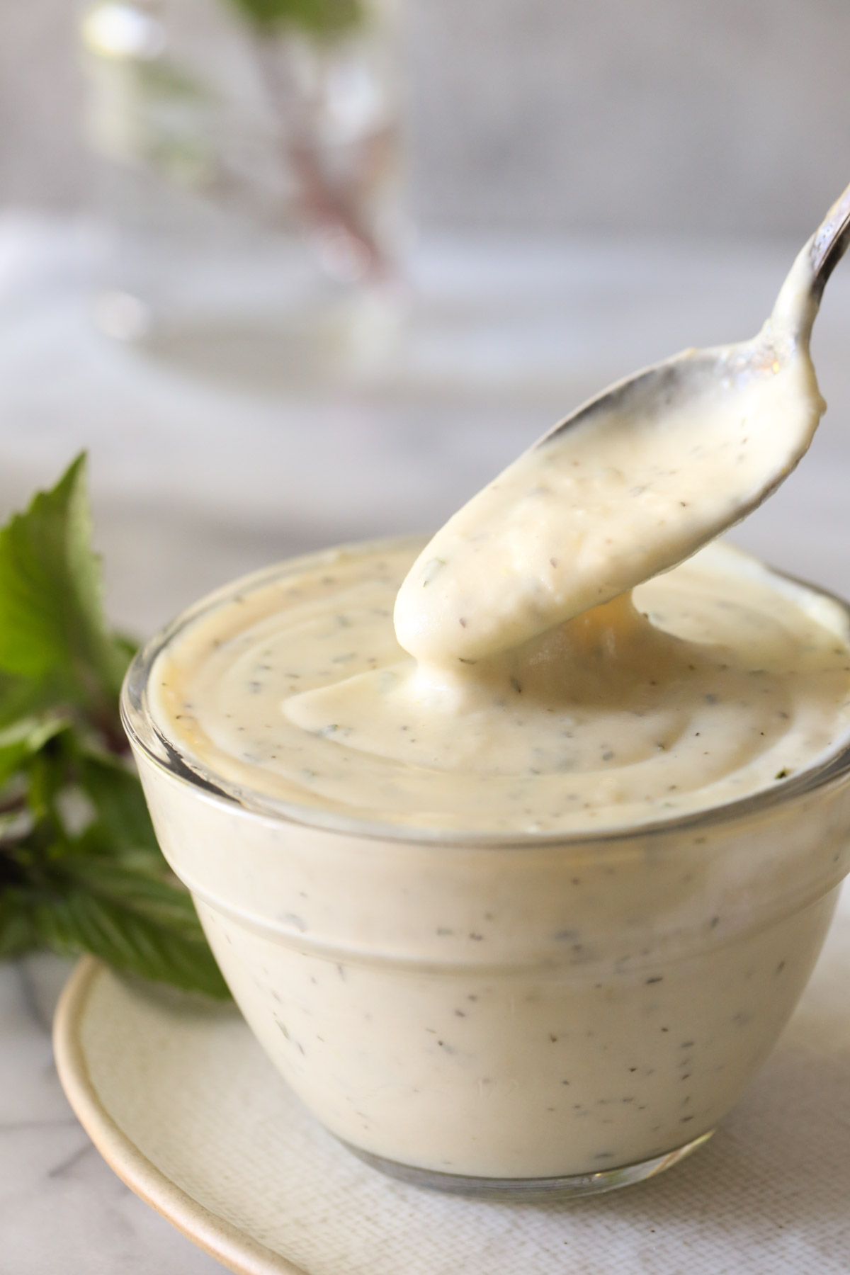 A small glass bowl of Homemade Cream of Chicken Soup sitting on a plate, with a spoon full of the soup being removed.