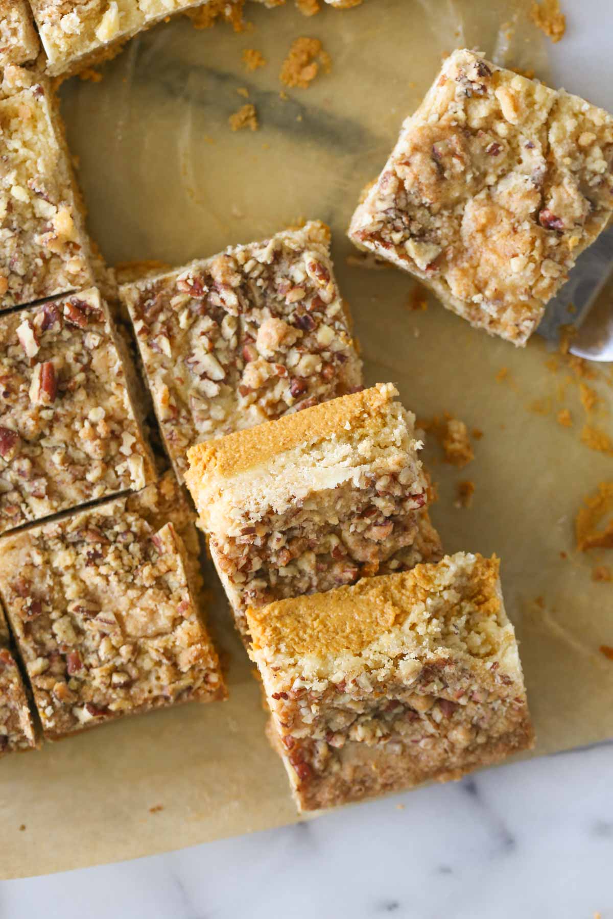 Overhead shot of cut Pumpkin Pie Bars on parchment paper. 