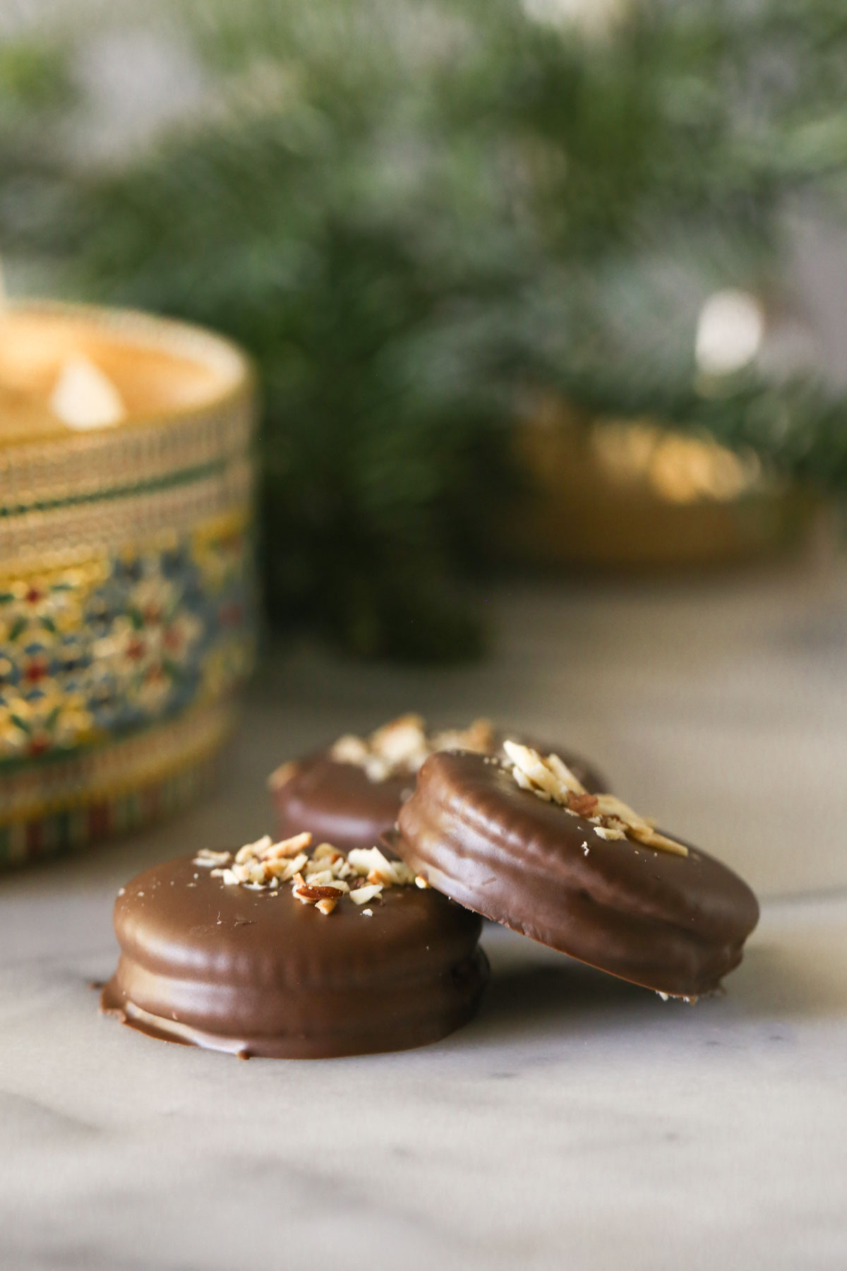 Close up shot of three Ritzy Rolo Cookies, with the cookie tin in the background.