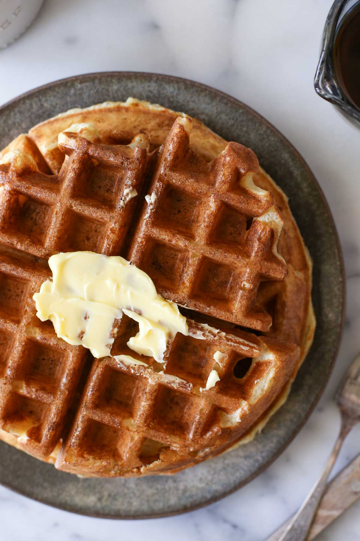Close up shot of Overnight Sourdough Waffles on a plate with butter on top.  