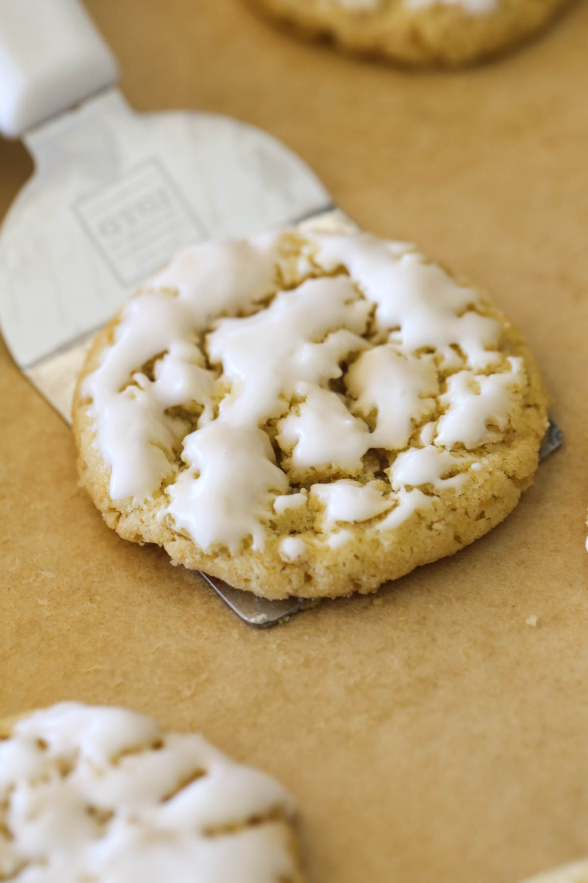 Close up shot of a spatula under an Iced Lemon Oatmeal Cookie.
