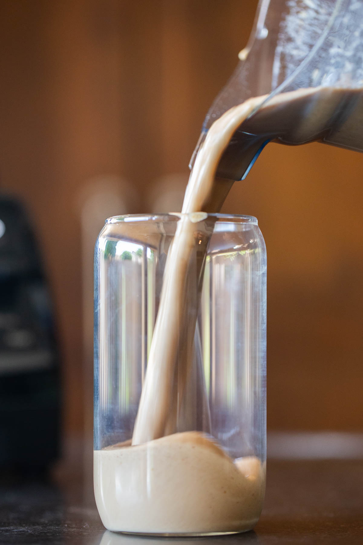A Copycat Sprouts Date Coffee Smoothie being poured from the blender into a tall glass.