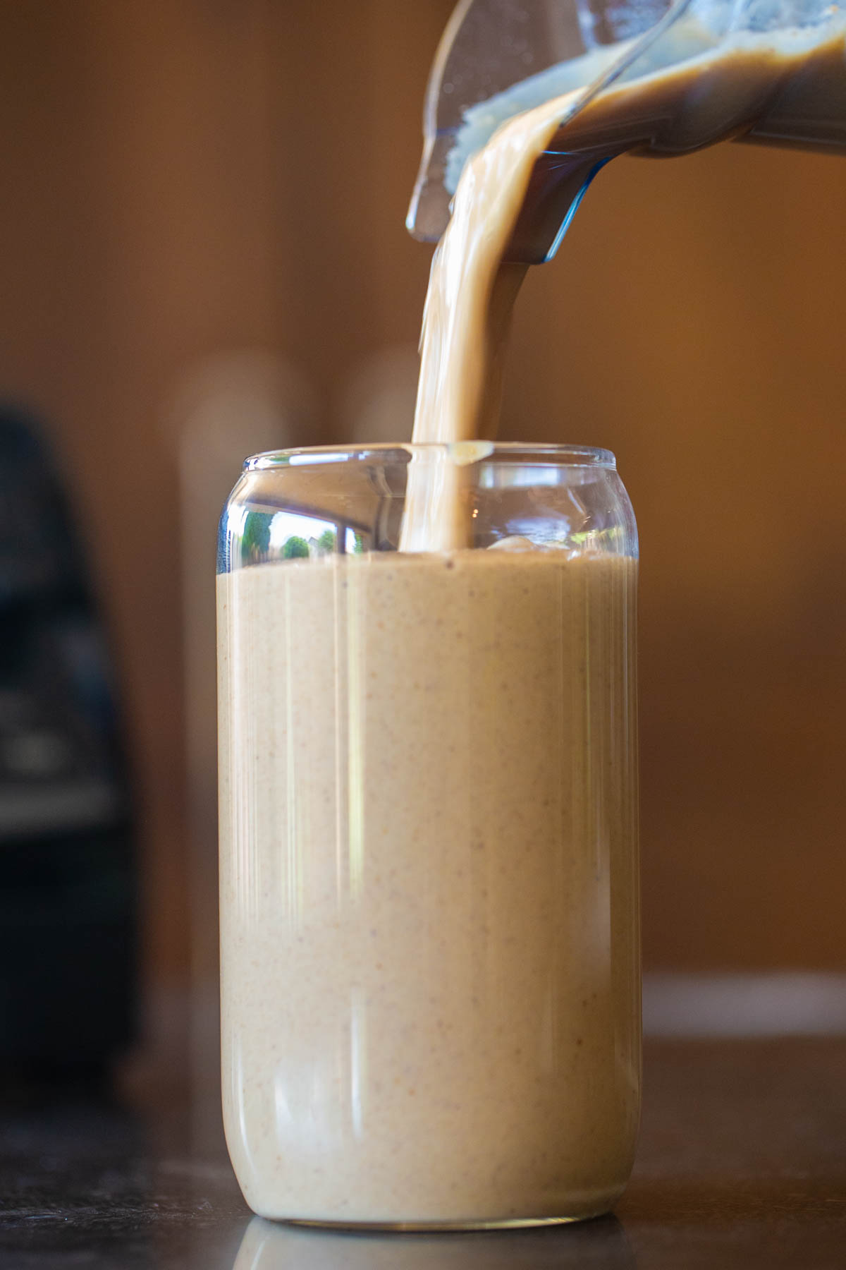 A Copycat Sprouts Date Coffee Smoothie being poured from the blender into a tall glass.