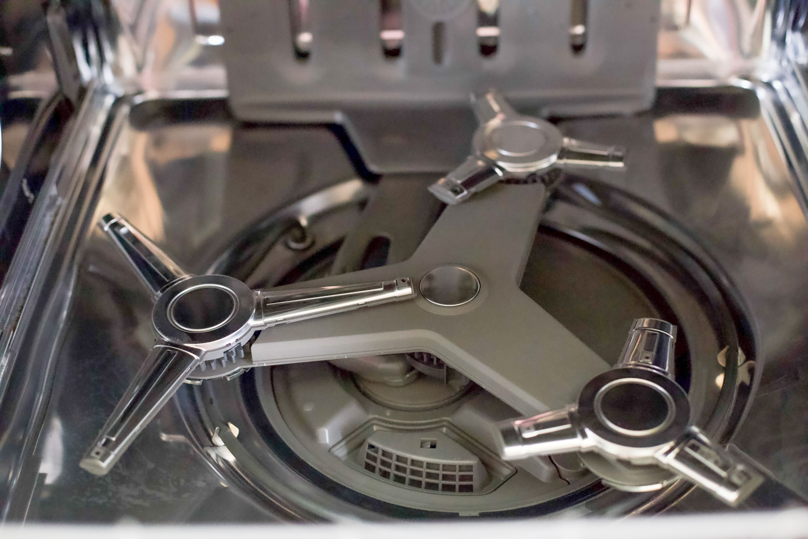Close-up of the stainless steel interior and spray arms inside an empty dishwasher.